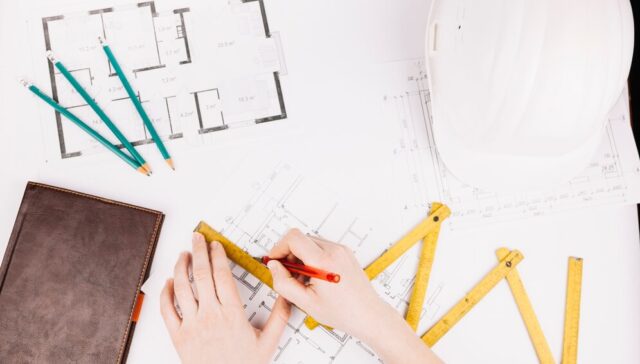 Architect performing traditional hand drafting with pencils and drawing tools for design planning and as-built documentation.