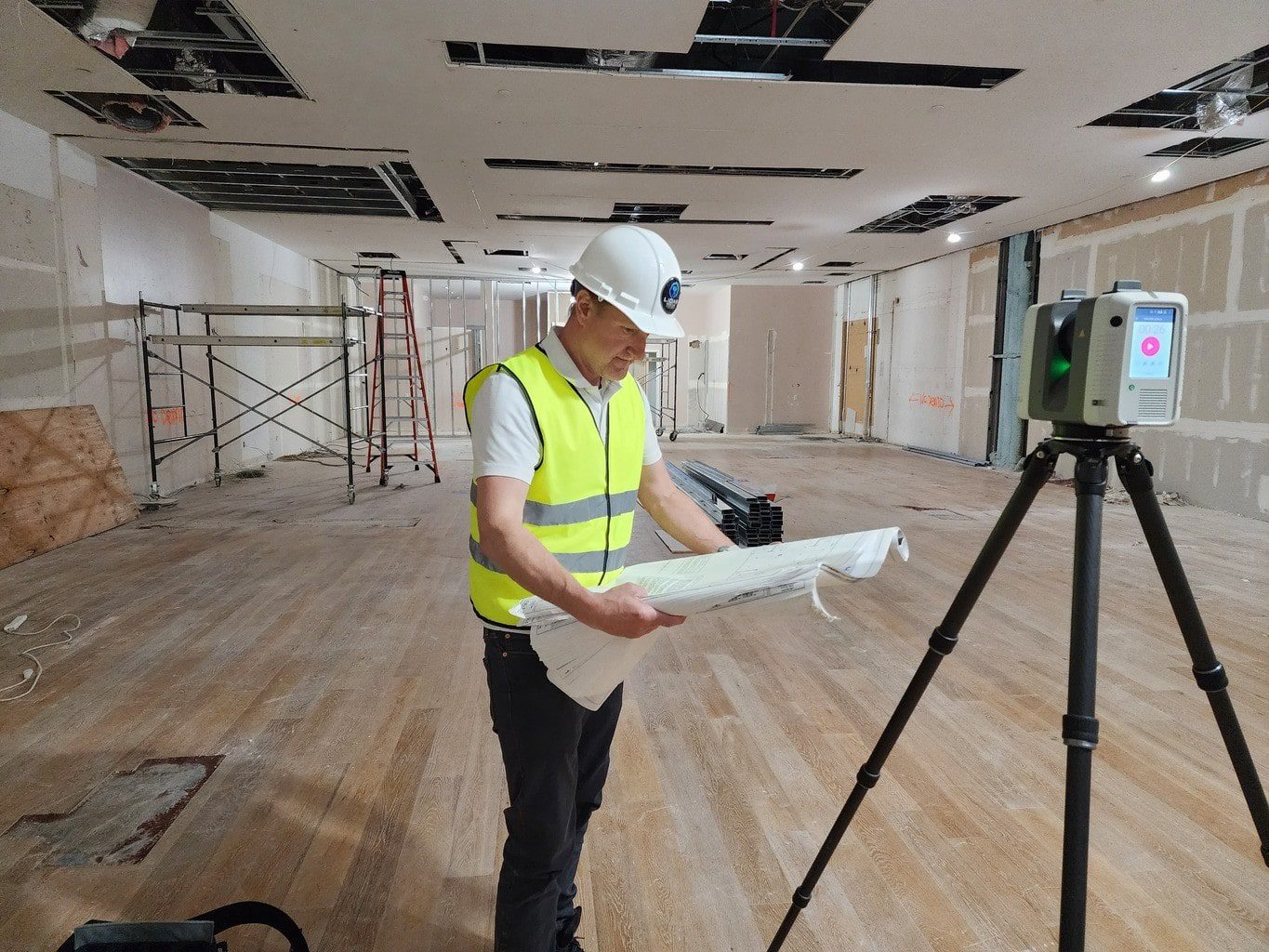 Scan technician reading plans and performing 3D laser scanning in a retail space for accurate as-built documentation